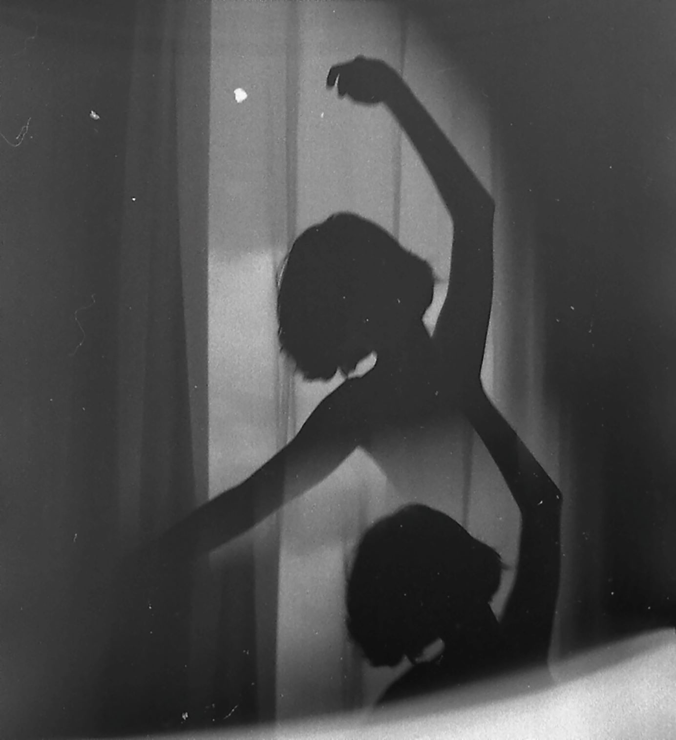 black and white image of a woman and her shadwow dancing in front of a window